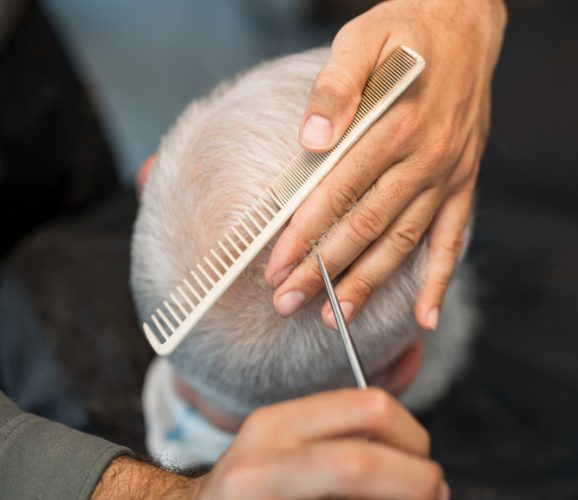 high-angle-barber-giving-elder-male-client-haircut